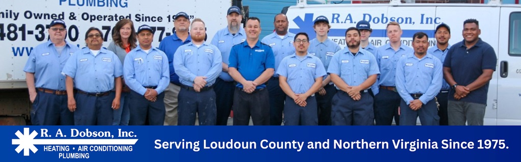 team plumbers with hands at their waist, standing in front of service vehicles